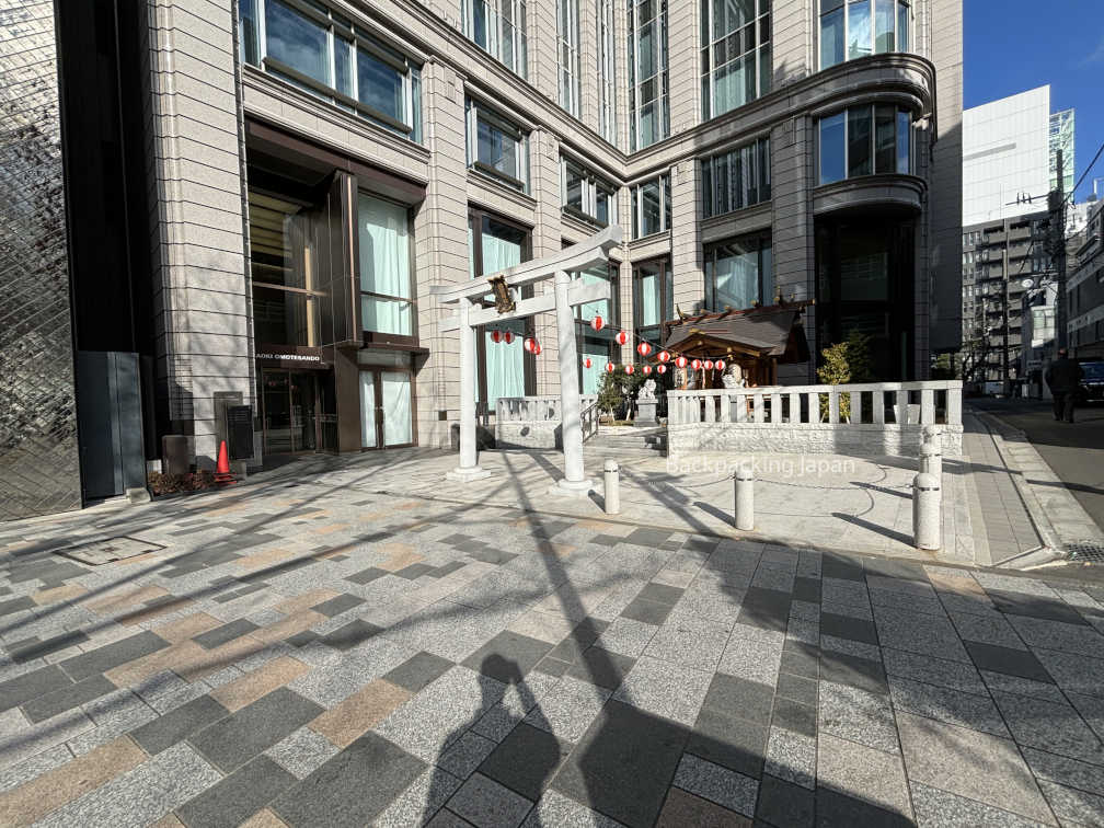 A small shrine next to gigantic luxury buildings on the streets of Omotesando